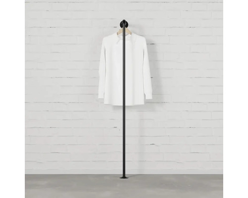 Stojan na oblečenie so zavesenou košeľou pred stenou