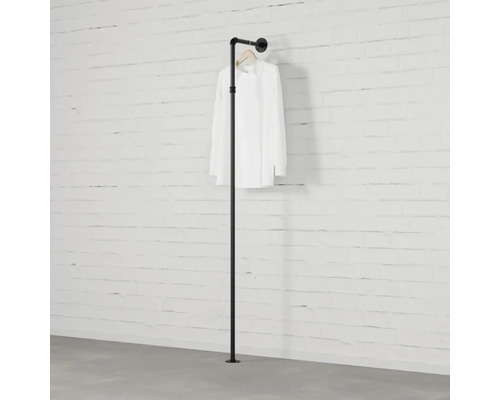 Čierna tyč na oblečenie z rúrok pred tehlovou stenou s košeľou.