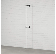 Čierny kovový vešiak na šaty z rúrok pri bielom tehlovom múre