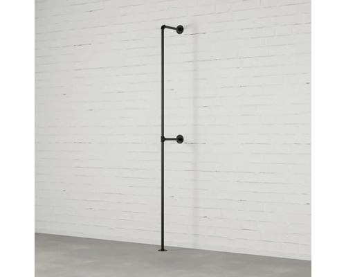 Čierny kovový vešiak na šaty z rúrok pri bielom tehlovom múre