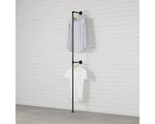 Železný rúrkový vešiak na šaty s dvomi košeľami visiacimi pred bielym tehlovým múrom