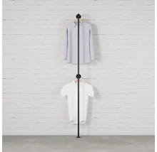 Čierny vešiak na oblečenie s dvoma kusmi oblečenia pred tehlovou stenou