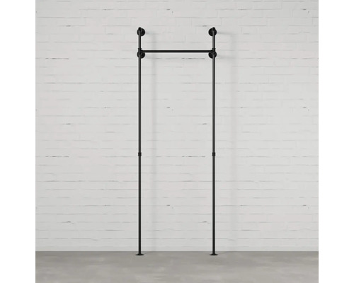 Čierny vešiak na oblečenie z kovových rúrok pred bielou tehlovou stenou