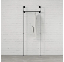 Čierna šatníková tyč z rúrok s odevom pred tehlovou stenou