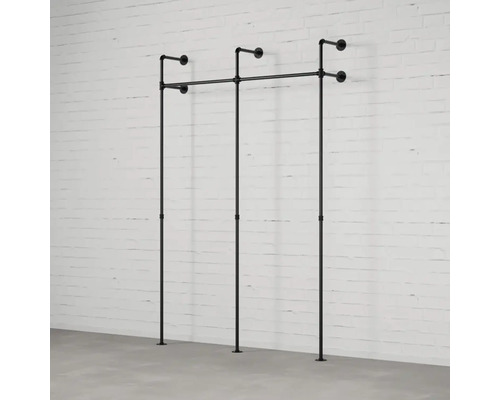 Nástenný vešiak na oblečenie z rúrok pred tehlovou stenou