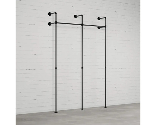 Nástenná šatňa z rúrok pred tehlovou stenou