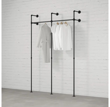 Voľne stojace vešiaky na šaty z rúrok s oblečením pred tehlovou stenou