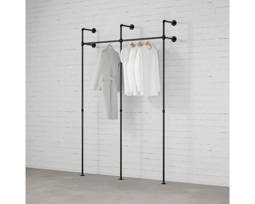 Voľne stojace vešiaky na šaty z rúrok s oblečením pred tehlovou stenou