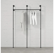 Čierny stojan na šaty z rúrok s oblečením pri stene