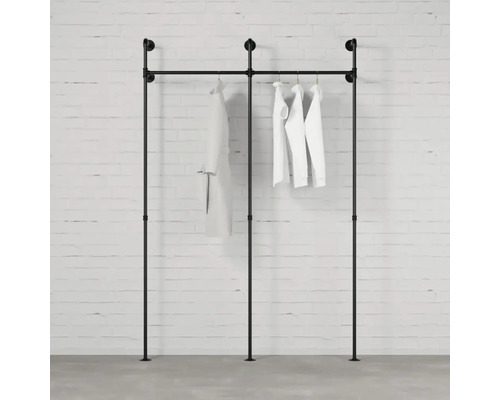 Čierny stojan na šaty z rúrok s oblečením pri stene