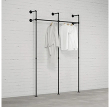 Čierny vešiak na oblečenie s oblečením pred tehlovou stenou