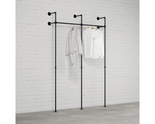 Čierny vešiak na oblečenie s oblečením pred tehlovou stenou