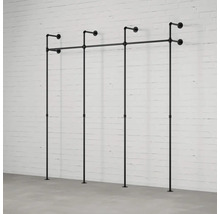 Čierny kovový vešiak na oblečenie z rúrok pred bielou tehlovou stenou