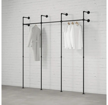 Čierny rúrkový systém na šaty so zaveseným oblečením pred tehlovou stenou