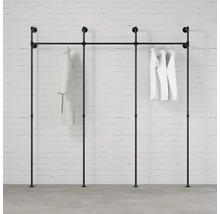 Čierny vešiak na oblečenie z rúrok s bielym oblečením na tehlovej stene