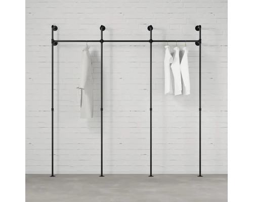 Čierny vešiak na oblečenie z rúrok s bielym oblečením na tehlovej stene