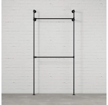 Čierny kovový vešiak na šaty pred tehlovou stenou