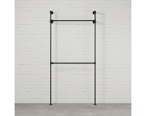 Čierny kovový vešiak na šaty pred tehlovou stenou