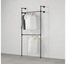 Dvojradový vešiak na šaty z kovových rúrok so zaveseným oblečením pred tehlovou stenou