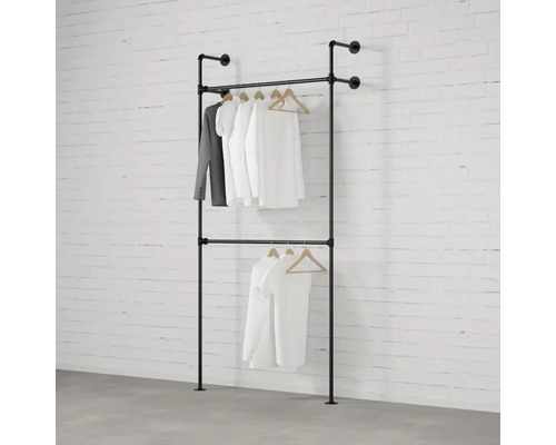 Dvojradový vešiak na šaty z kovových rúrok so zaveseným oblečením pred tehlovou stenou
