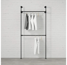 Stojan na oblečenie z rúrok so zaveseným oblečením pred tehlovou stenou