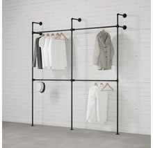 Vešiak na šaty z rúrok so zaveseným oblečením pred tehlovou stenou