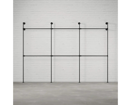 Čierny rúrkový systém vešiaka na šaty pred tehlovou stenou