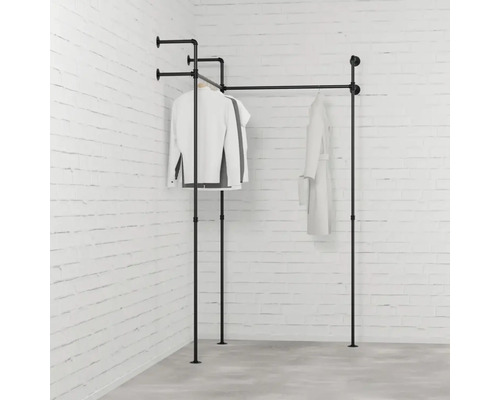 Čierny vešiak na oblečenie z kovových rúrok s oblečením pred tehlovou stenou
