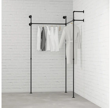 Čierny kovový rúrkový vešiak na oblečenie s oblečením pred tehlovou stenou