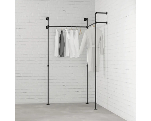 Čierny kovový rúrkový vešiak na oblečenie s oblečením pred tehlovou stenou