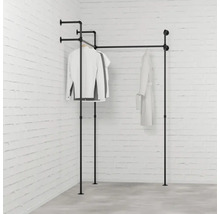 Vešiak na oblečenie z kovových rúrok so zaveseným oblečením pred tehlovou stenou