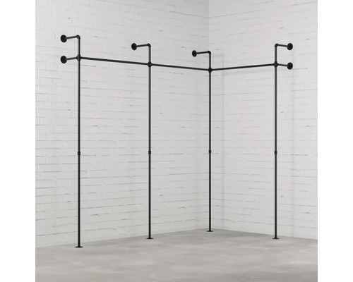 Vešiak na šaty z rúrok v rohovej izbe pred tehlovou stenou