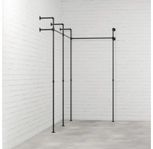 Čierna konštrukcia vešiaka na šaty z rúrok pred tehlovou stenou