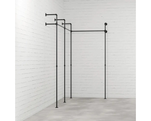 Čierna konštrukcia vešiaka na šaty z rúrok pred tehlovou stenou