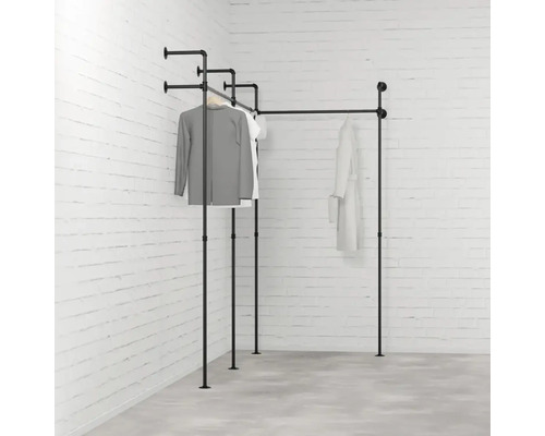 Čierny kovový rúrkový vešiak na oblečenie v rohovej izbe s oblečením
