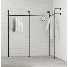 Čierny šatníkový systém s oblečením pred bielou tehlovou stenou