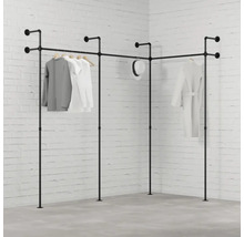 Rohový vešiak na šaty z rúrok s oblečením pred tehlovou stenou