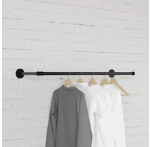 Čierna šatníková tyč s oblečením na tehlovej stene