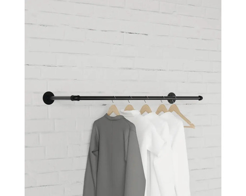 Čierna šatníková tyč s oblečením na tehlovej stene