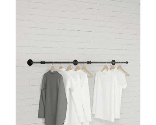 Nástenný vešiak s oblečením visiacim pred tehlovou stenou