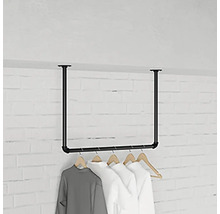 Stojan na šaty z oceľových rúrok s visiacim oblečením pred tehlovou stenou