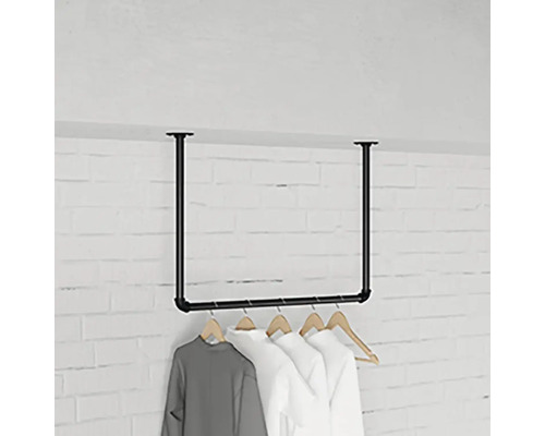 Stojan na šaty z oceľových rúrok s visiacim oblečením pred tehlovou stenou