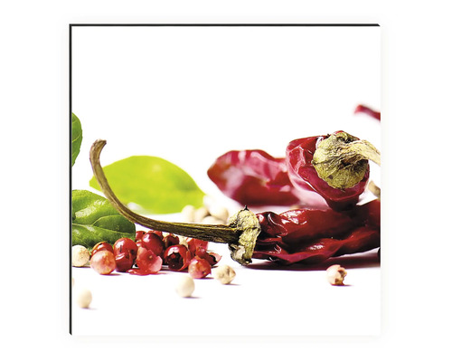 Chilli papričky, zelené listy a rôzne zrnká korenia ležia na svetlom povrchu.