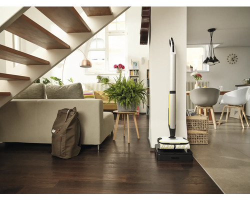 Svetlá obývacia izba so schodiskom, pohovkou, izbovou rastlinou, batohom a akumulátorovým mopom