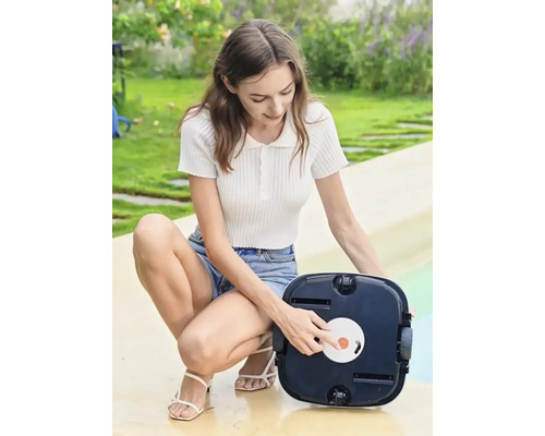 Žena obsluhuje automatický čistič bazénov v záhrade.