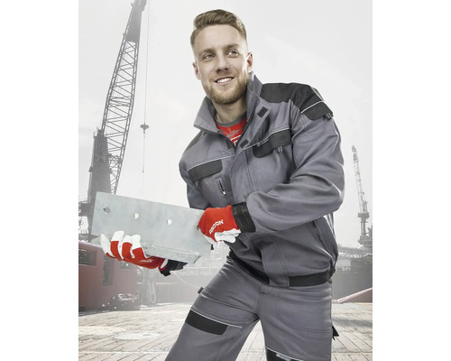 Muž v pracovnom odeve s kovovým nosníkom pred žeriavom