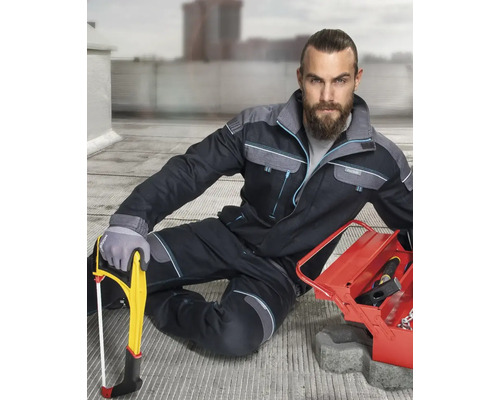 Remeselník s pracovnými nohavicami, chvostovou pílou a kufríkom na náradie na stavenisku.