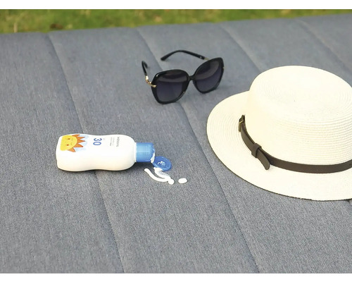 Krém na opaľovanie, klobúk a slnečné okuliare ležia na sivom pozadí.