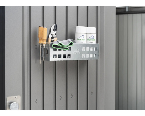 Polica so záhradným náradím a sprejmi na sivej stene