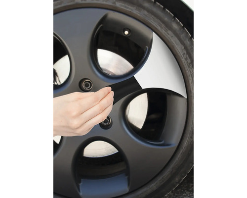 Osoba lepí lepiacu pásku na koleso auta